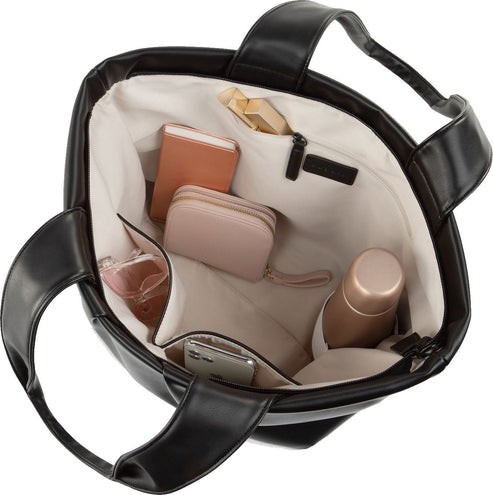 Open black tote bag, overhead view, reveals light lining, zippered compartment, and pockets holding a peach wallet, a pink wallet, perfume, water bottle, a smartphone, and a snack.