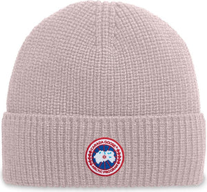 Knit beanie hat in light pink with a circular badge emblem.