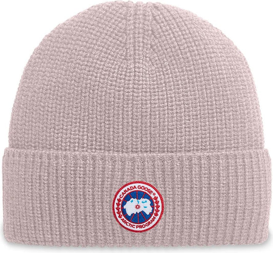 Knit beanie hat in light pink with a circular badge emblem.
