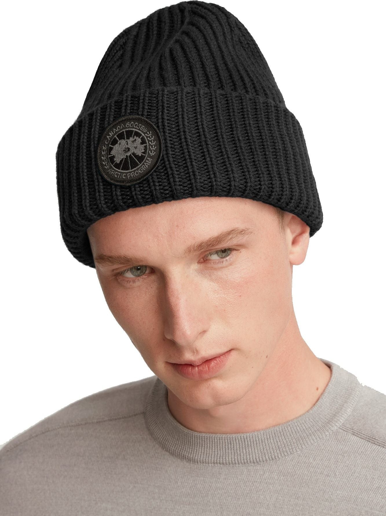Person wearing a black ribbed beanie with a circular badge.