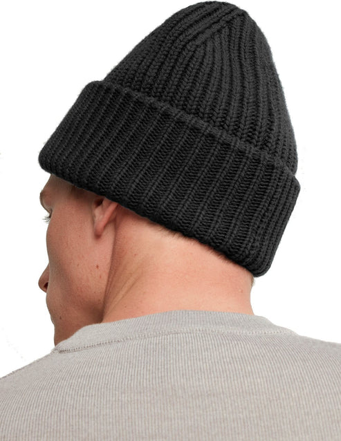 Close-up of a person wearing a dark gray ribbed beanie.