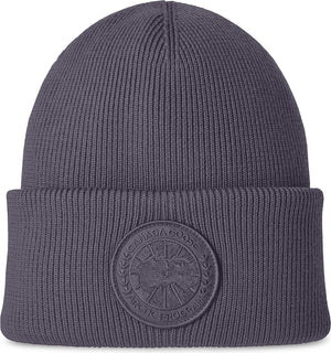 Gray knit beanie hat with circular emblem.