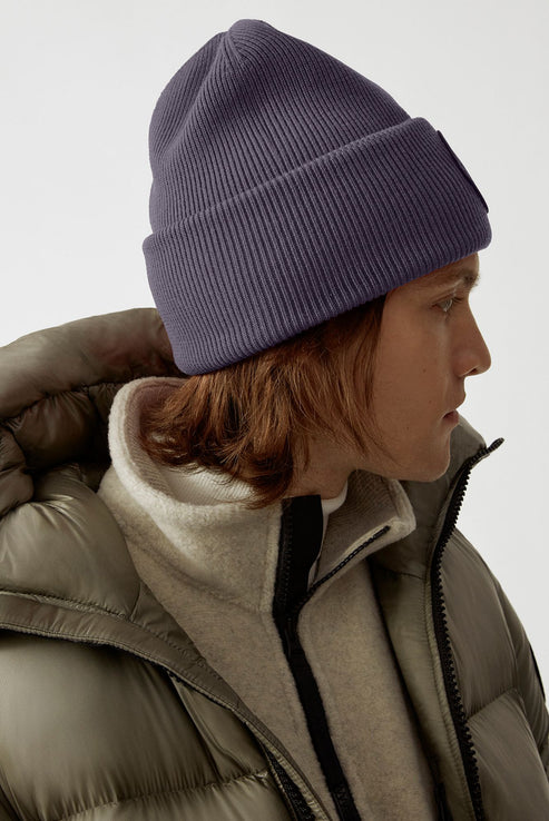 Person wearing a dark blue knit beanie and a green puffer jacket.