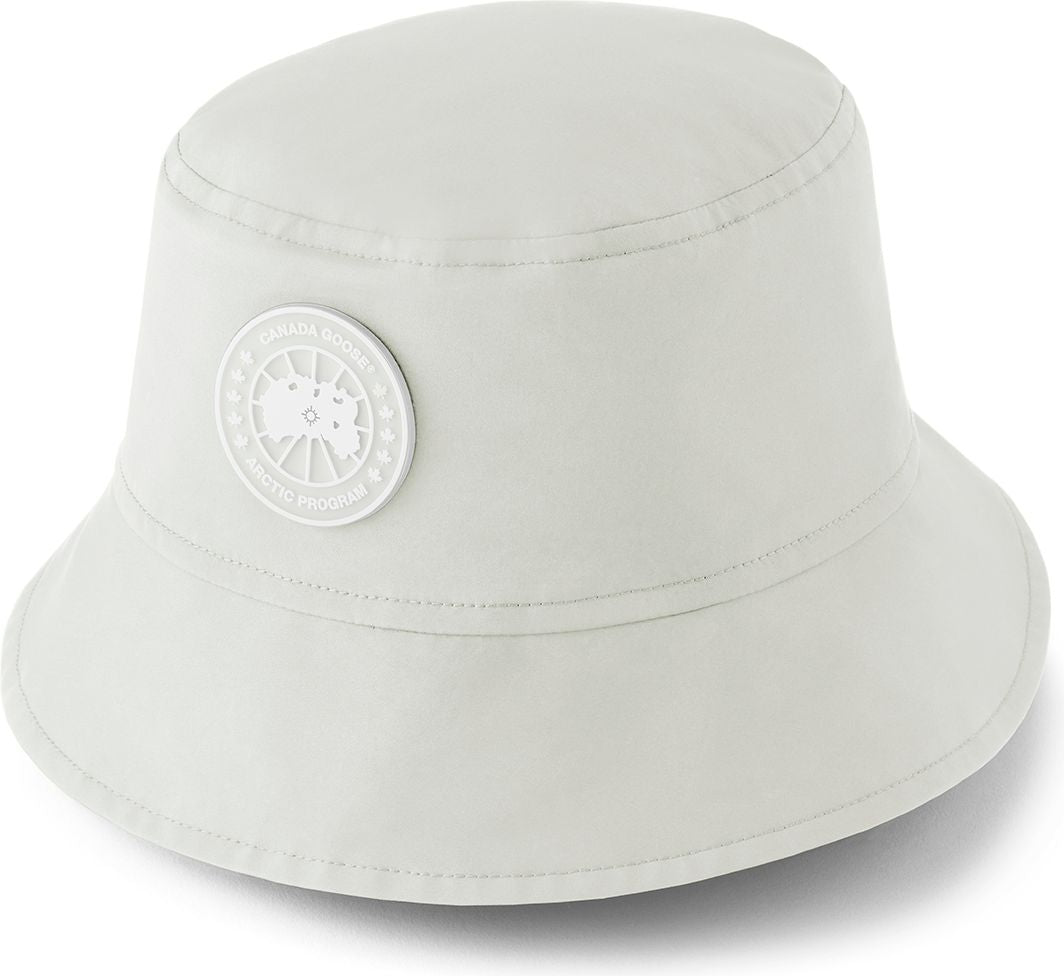 White bucket hat with a round, white emblem on the side.