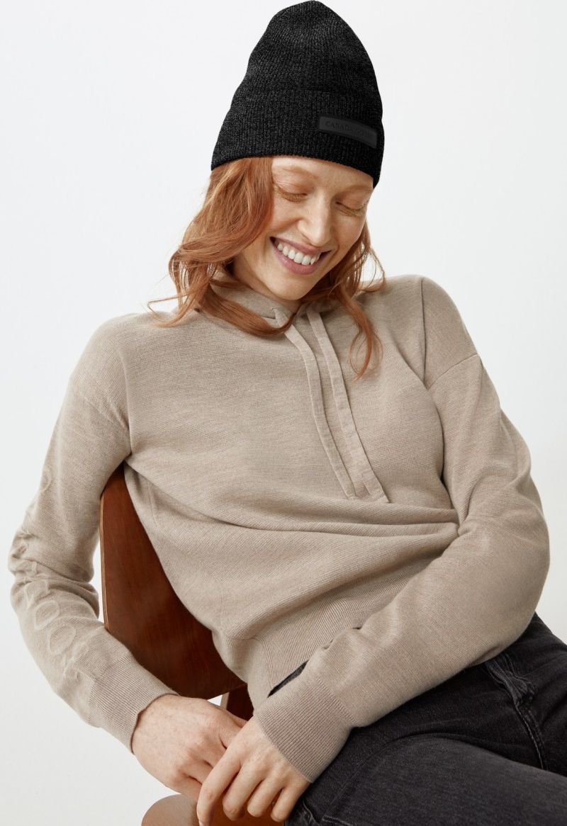 Woman with a black beanie and beige hooded sweater