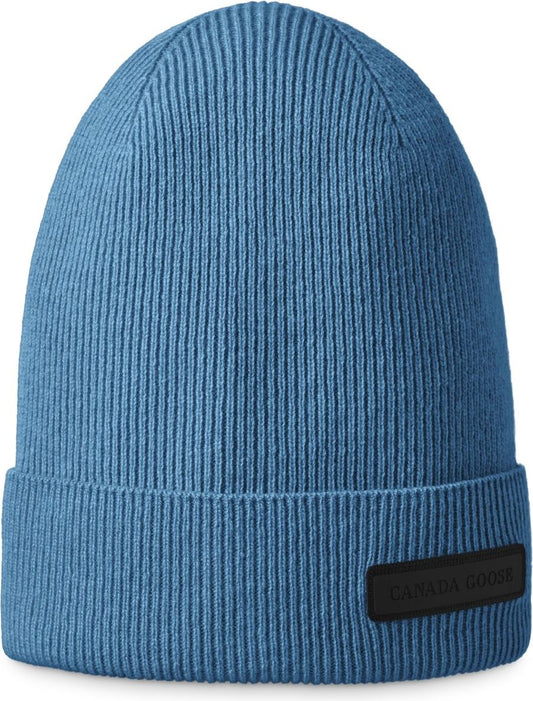 Knitted ribbed light blue beanie with a folded brim and a black rectangle patch with white text.