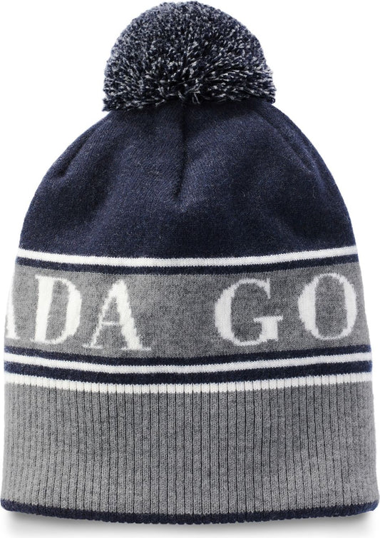 Knitted beanie with a pom-pom, featuring gray and navy stripes, with the letters 'ADA GO' in white across the middle gray stripe.