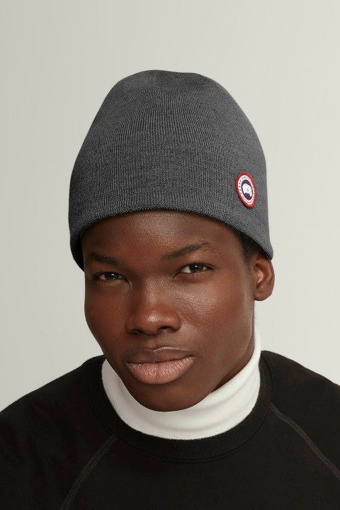 Close-up of a person wearing a gray beanie with circular logo patch.