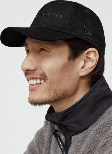 Man wearing a black baseball cap with tonal "CANADA GOOSE" embroidery.