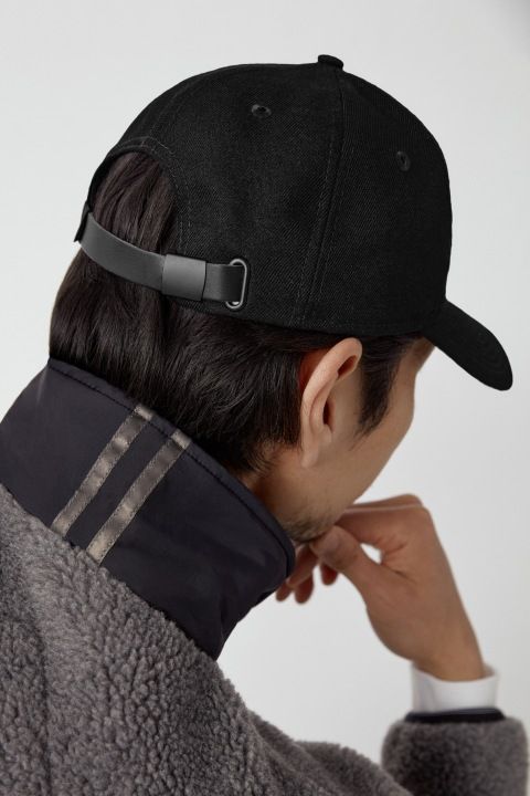 Person wearing a black baseball cap with adjustable strap.