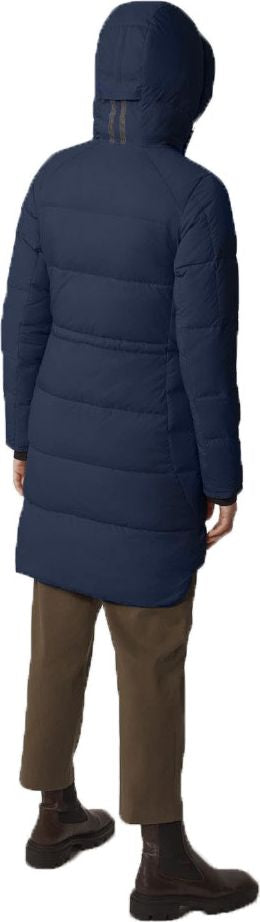 A person wearing a navy blue puffer coat with a hood, brown pants, and brown shoes.