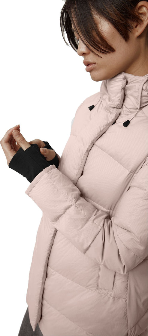 A person in a light pink puffer coat with black wrist cuffs.