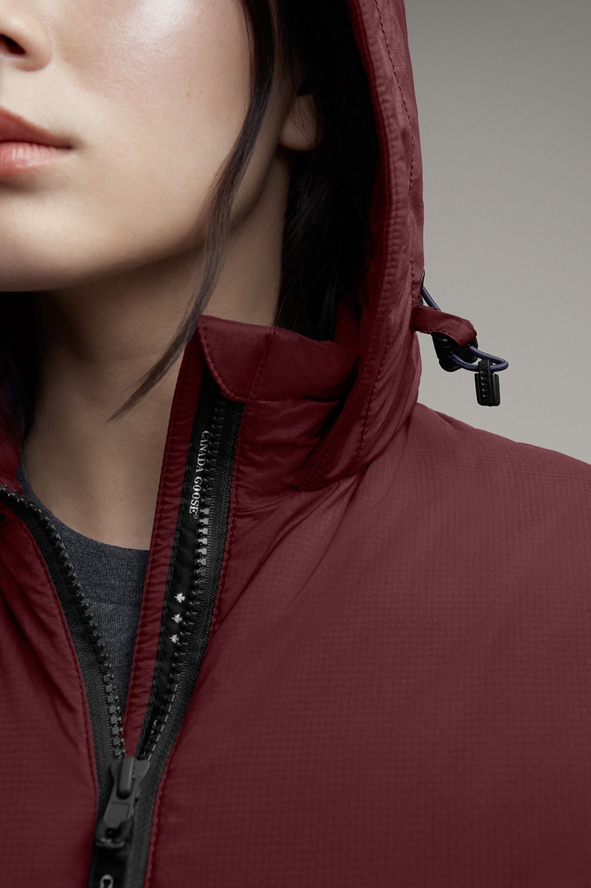 Close-up of a maroon hooded jacket with a black zipper.