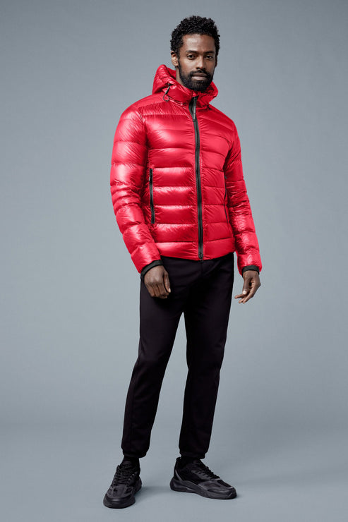 A black man wearing a bright red puffer jacket with a hood, black athletic pants and black running shoes.