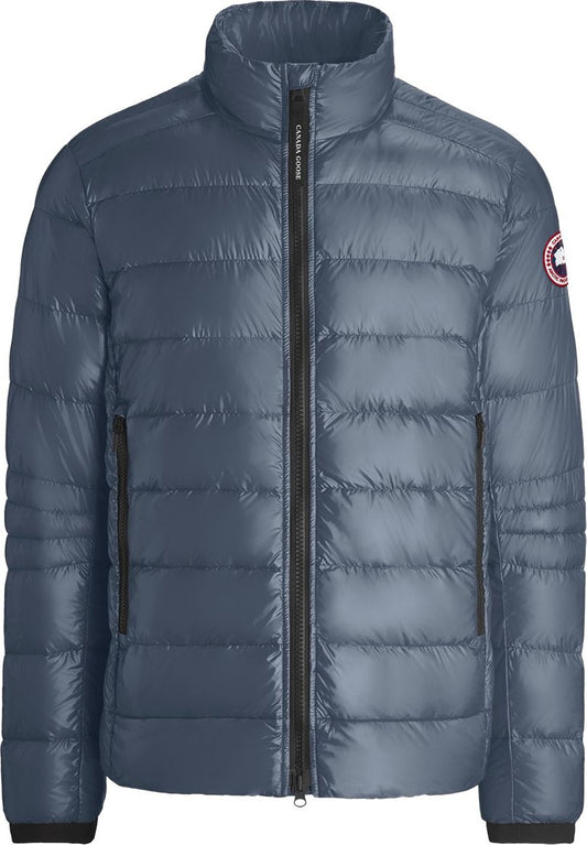 Blue puffer jacket with a front zipper and a circular logo patch on the left sleeve.