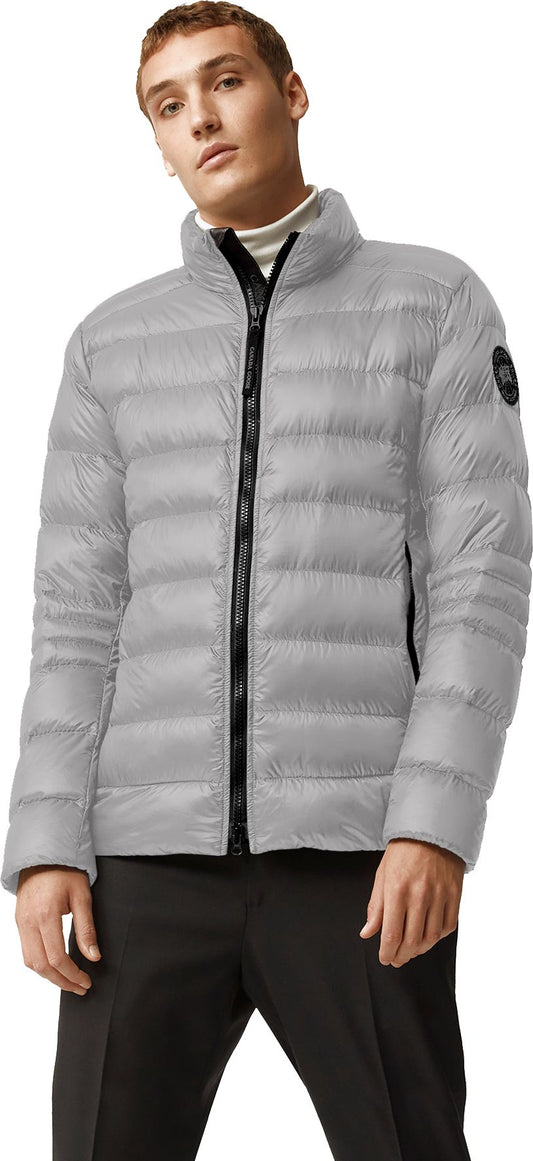 A man in a grey puffer jacket with a black zipper and black pants.