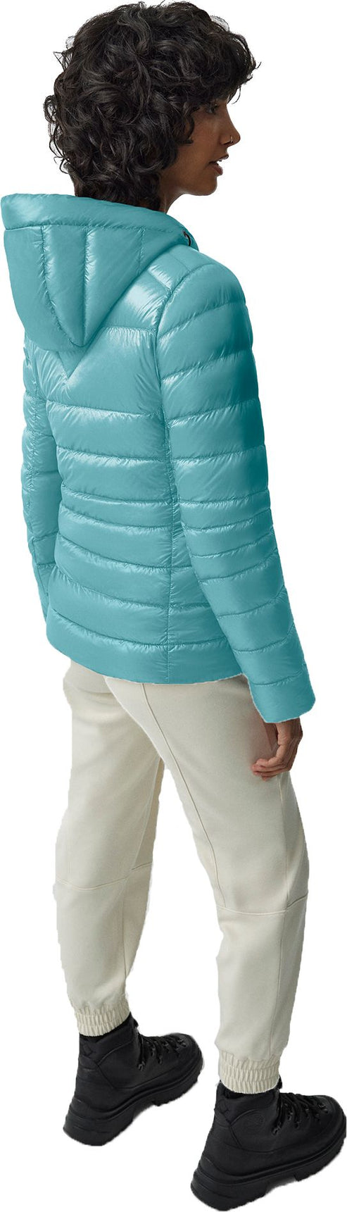 A person wearing a blue hooded puffer jacket, beige pants, and black sneakers.