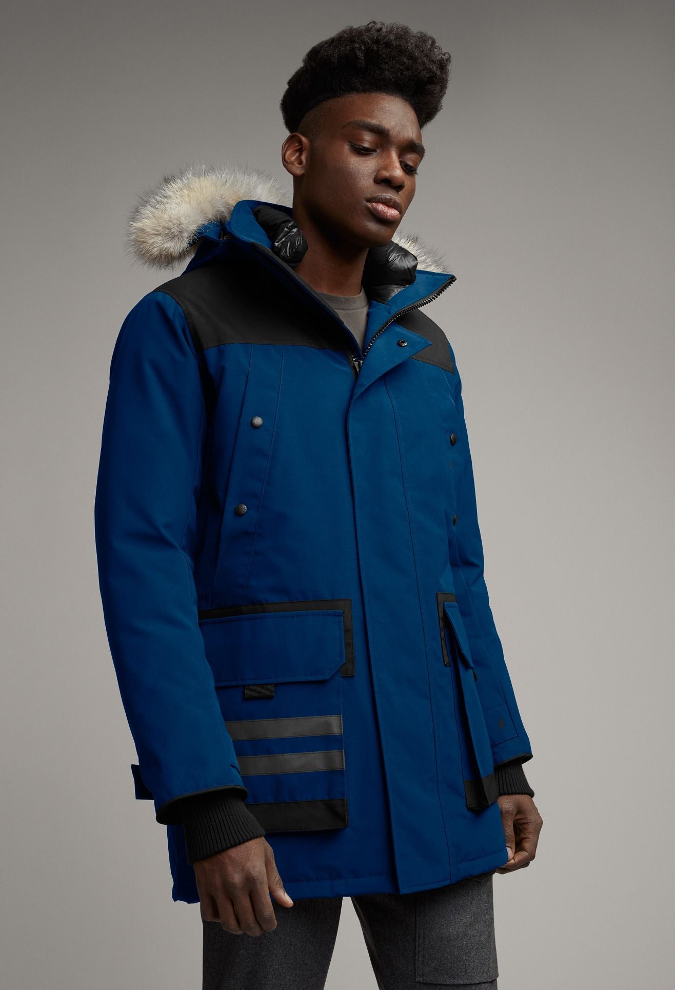 A person is wearing a blue parka with a fur trimmed hood.
