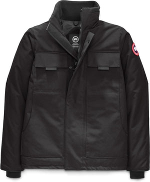 Black jacket with a stand-up collar, two flapped breast pockets, a circular logo patch on the upper left sleeve, and a snap-front closure.