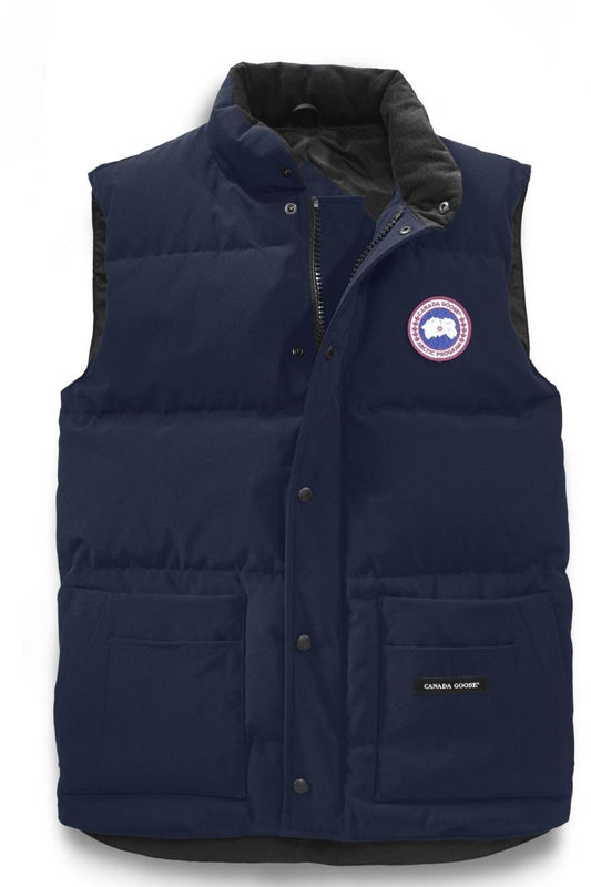 Navy blue down puffer vest with front pockets and a circular badge on the chest.