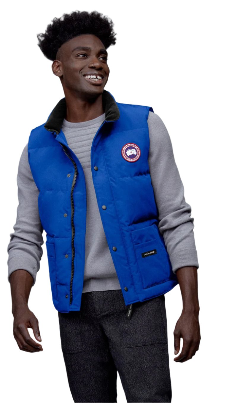 Man in blue down vest over gray sweater, smiling.