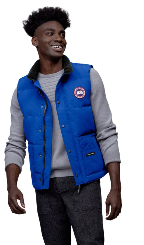 Man in blue down vest over gray sweater, smiling.