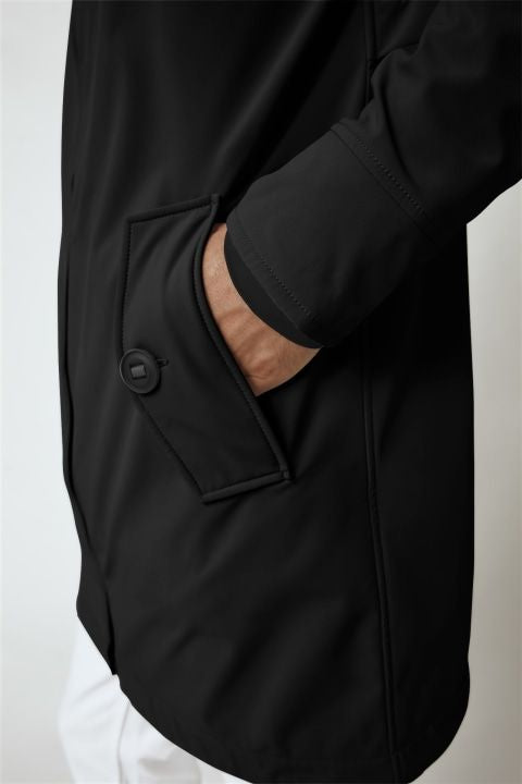 A close-up of a black coat with a person's hand reaching into the pocket.