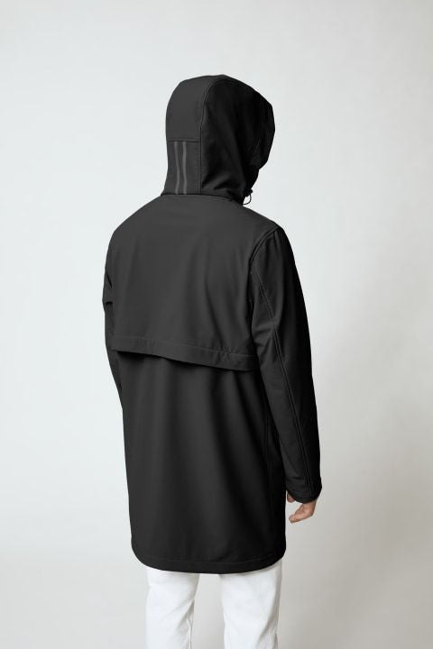 A person with their back facing the camera wearing a black hooded jacket and white pants.