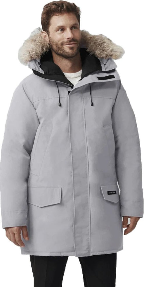 A man wearing a grey winter parka with a fur-trimmed hood.