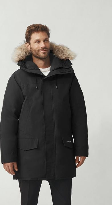 A man wearing a black parka with fur trim on the hood.