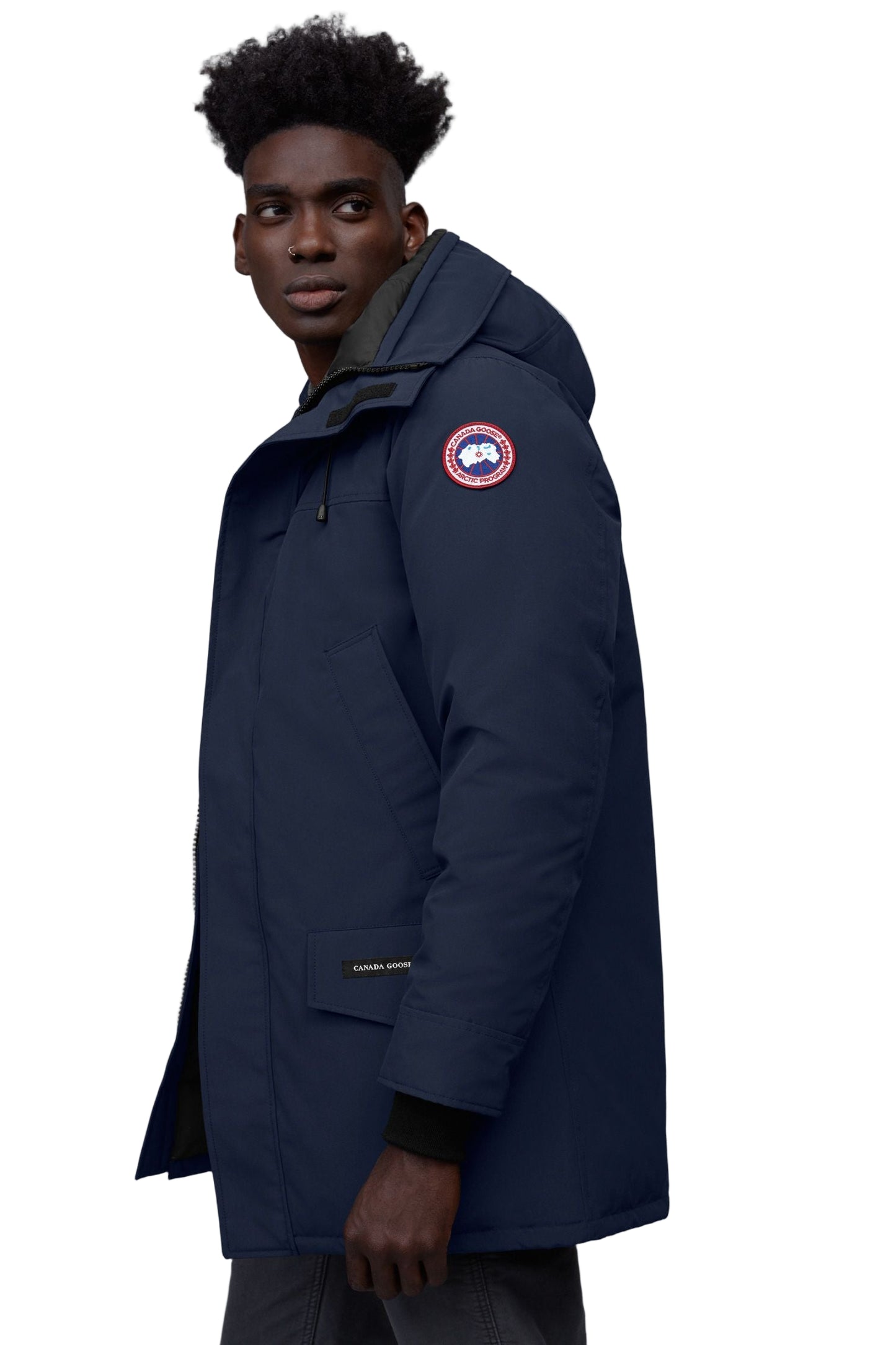 Man in navy parka jacket with hood and round patch.