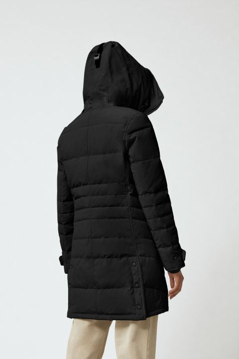A person is wearing a black hooded, mid-length, quilted puffer coat.