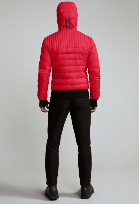 A person wearing a red hooded puffer jacket with black pants and shoes, shown from the back.