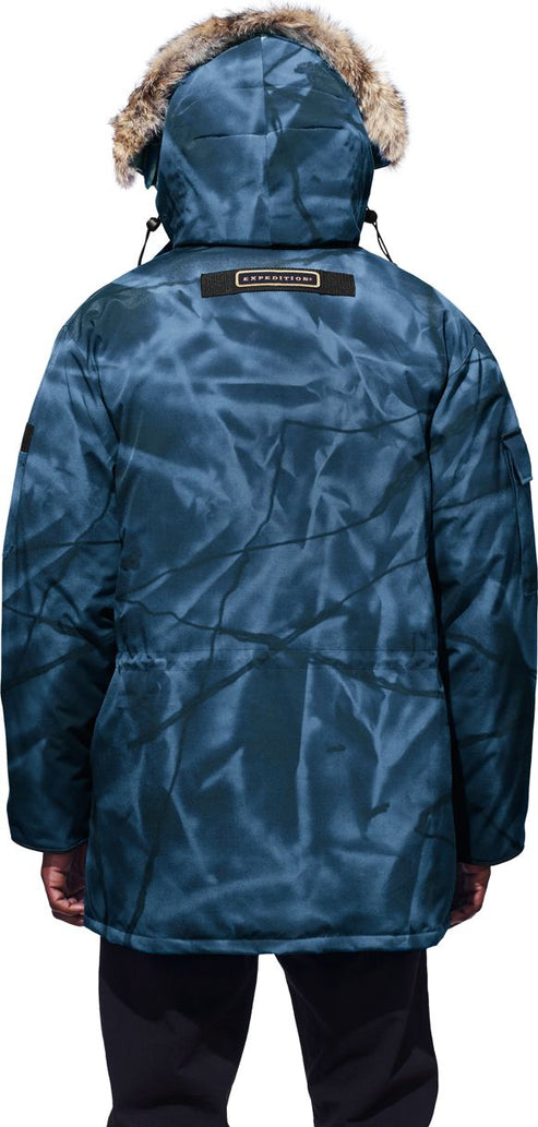 Back view of a person wearing a blue patterned parka with a fur-trimmed hood.
