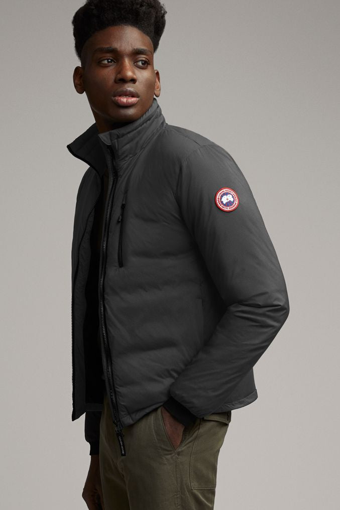 Man in black puffer jacket with logo patch and khaki pants.