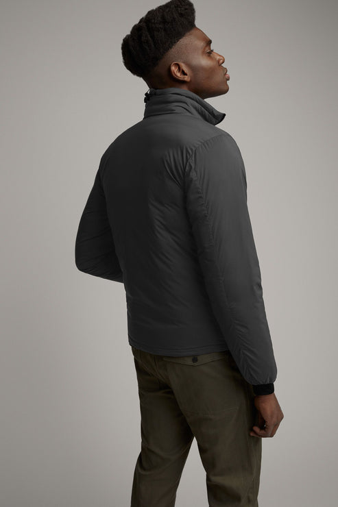 Man wearing a grey jacket and olive pants. The jacket has a high collar and is seen from the back.