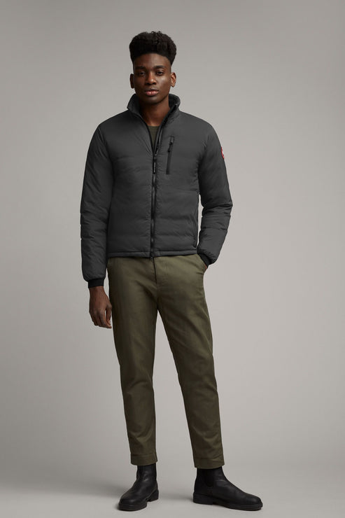 A man wearing a gray puffer jacket, green pants, and black shoes.