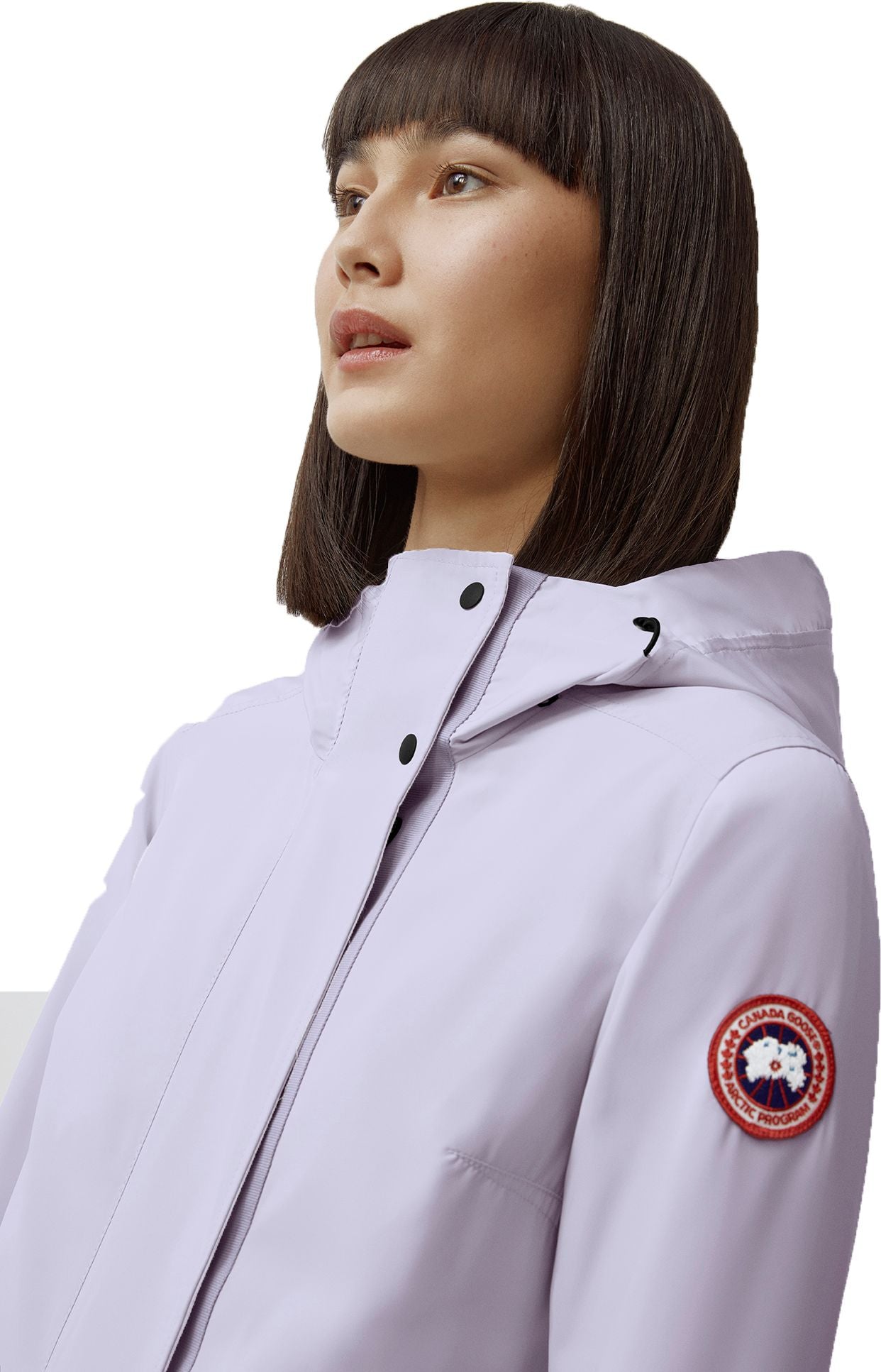Woman in a light purple hooded jacket with a circular emblem on the arm.