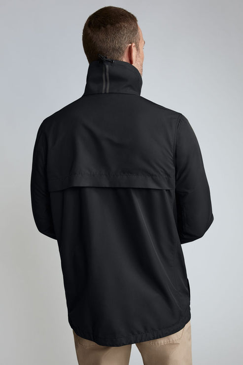 Rear view of a man wearing a black windbreaker jacket.