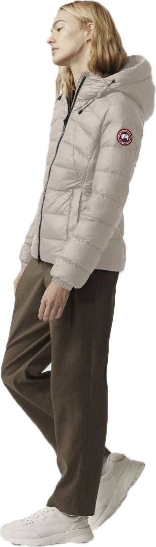 A person wearing a light gray puffer jacket, brown pants, and white sneakers.