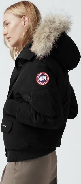 Black hooded jacket with fur trim and a round logo on the sleeve.