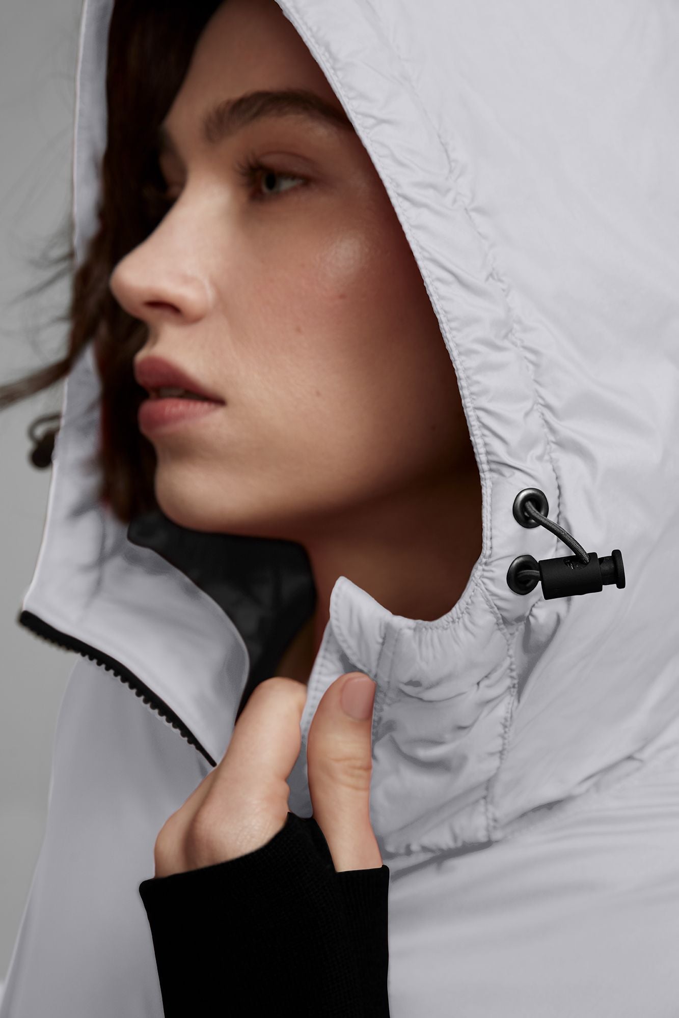 A person wearing a light grey hooded jacket with black toggles.