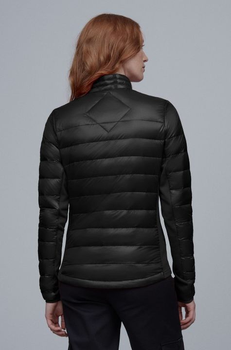 Back view of a black puffer jacket with a diamond-shaped quilted detail at the upper back, worn by a woman with red hair.