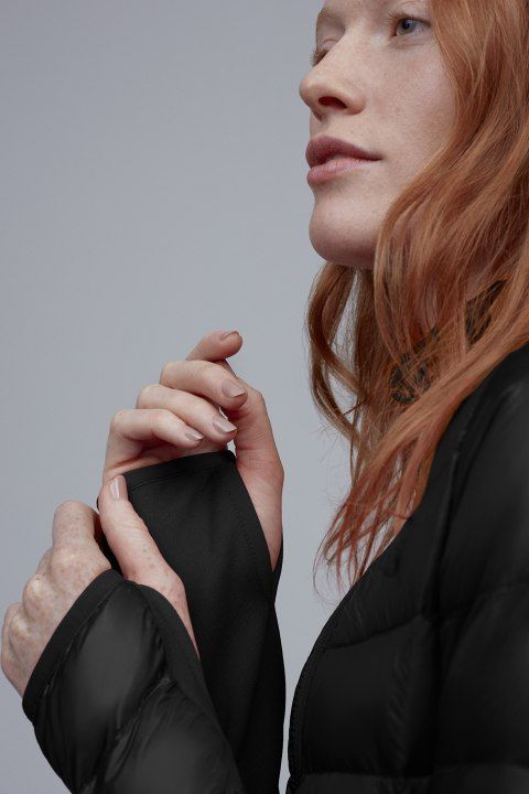 Close-up of a redhead in a black puffy jacket with built-in gloves.