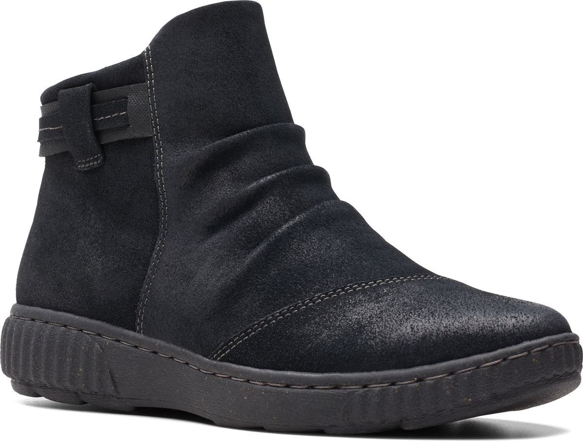 A black ankle boot with gathered fabric across the vamp and a low, ridged sole.