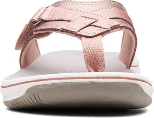 Close-up of a pink sandal with a t-strap, adjustable velcro strap and gray sole.