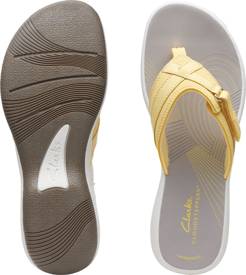 Pair of sandals, one showing a brown sole with a white arch support, the other showing a yellow strap and gray insole with radial design.