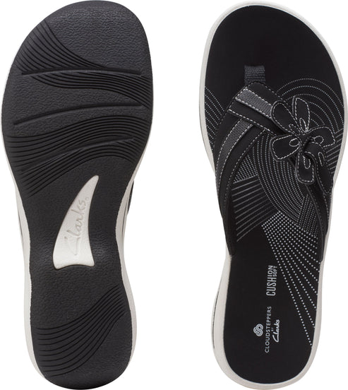 Two views of a black sandal with a toe thong and a white sole: sole view and flower detail of the upper.