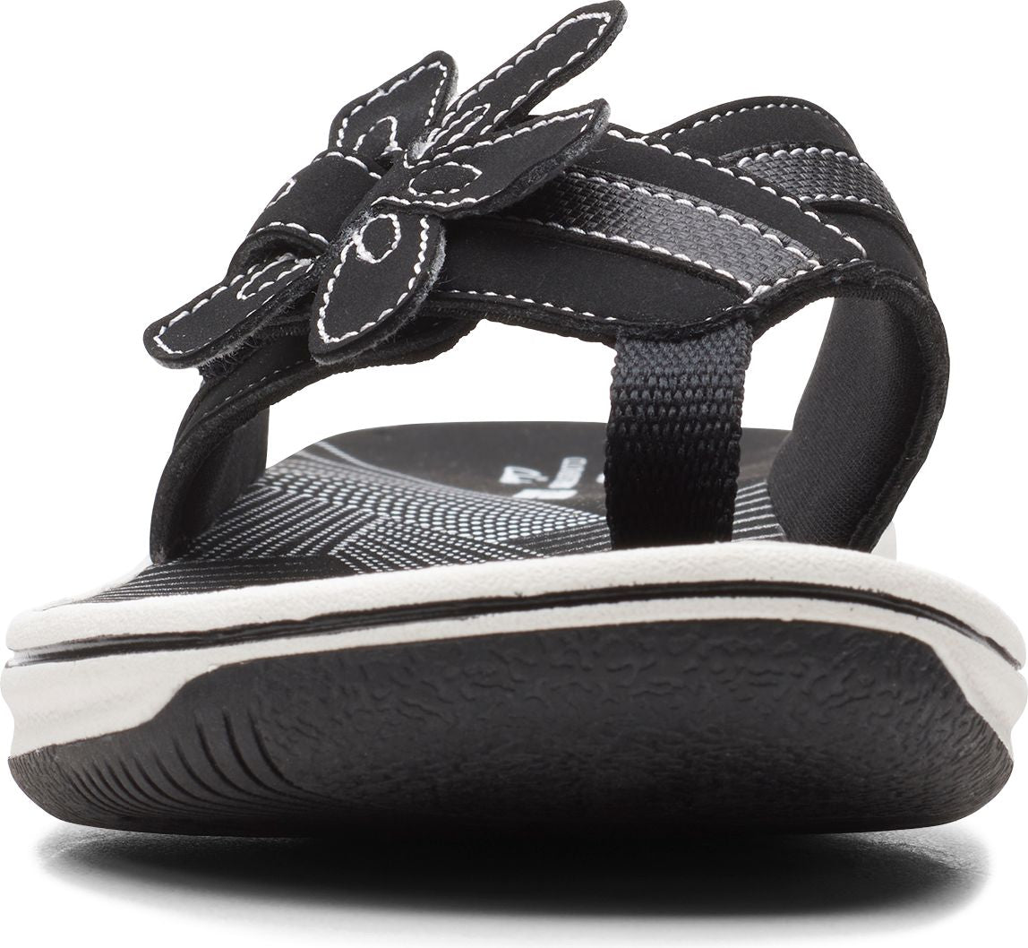 Black sandal with flower detail and white stitching.