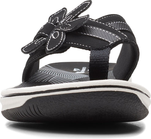 Black sandal with flower detail and white stitching.